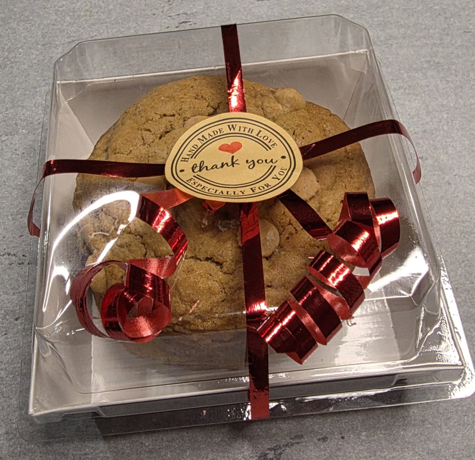 Cookie gift box tied with a red ribbon, finished with a stamped thank-you tag