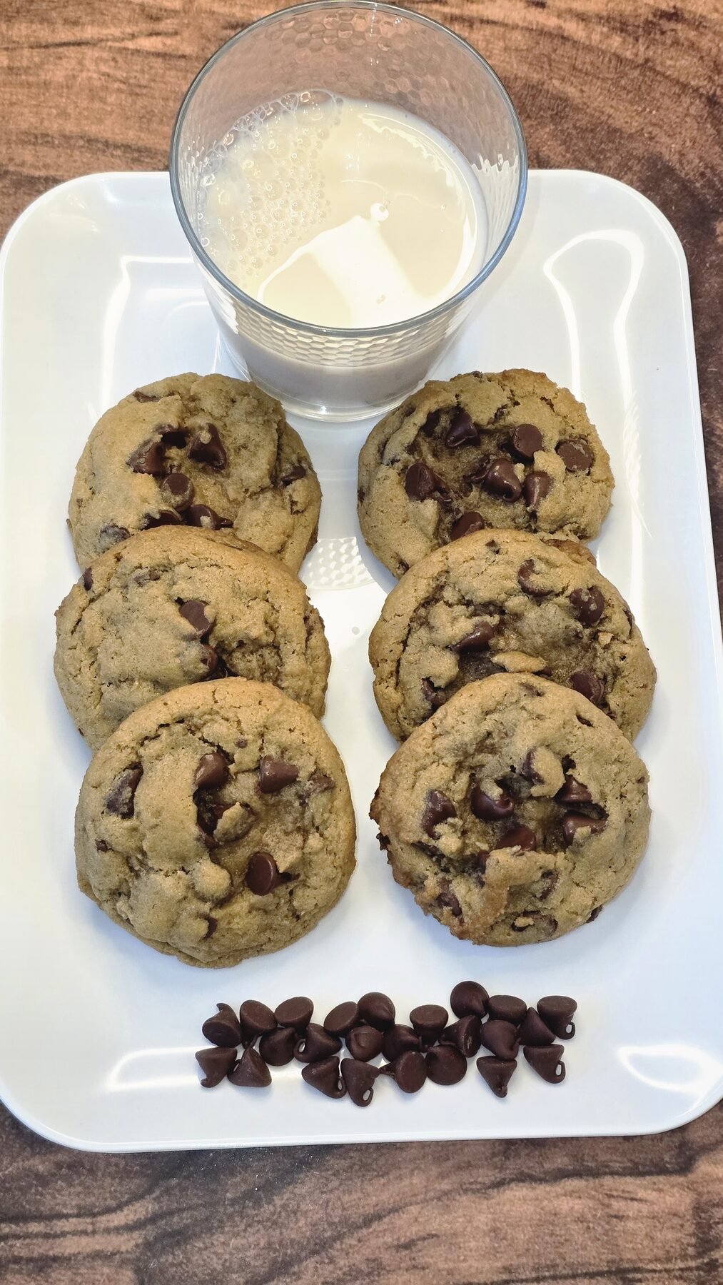 A tray of chocolate chip cookies with a glass of milk